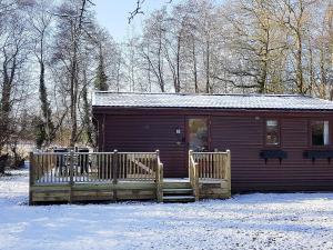 een klein huisje in de sneeuw met een houten hek bij Burnside Alderwood in Garboldisham