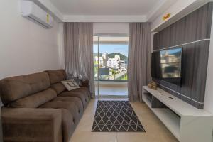 een woonkamer met een bank en een flatscreen-tv bij 006A - Apto novo 2 quartos em condomínio de luxo em Bombas in Bombinhas