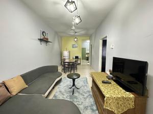 een woonkamer met een bank en een flatscreen-tv bij Triple J in Cameron Highlands