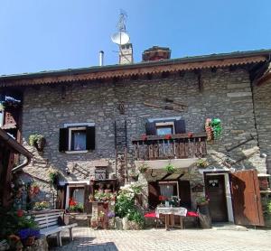 een stenen gebouw met een balkon en een tafel bij Le Grenier de Olga e Mario in Pré-Saint-Didier