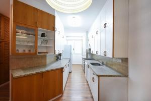 a large kitchen with white cabinets and a sink at Charming 2BR by HolyGuest in Tel Aviv