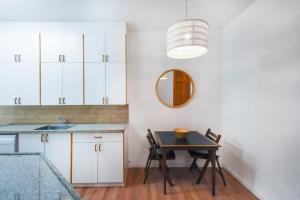 a kitchen with white cabinets and a table and a mirror at Charming 2BR by HolyGuest in Tel Aviv