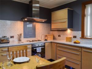 a kitchen with a wooden table with chairs and a sink at Bankhead Farm Cottage in Crossgates