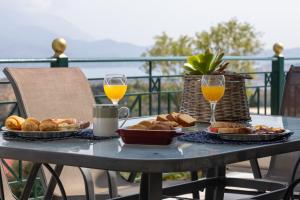 a table with two glasses of orange juice and bread at Villa Theano - Family House in Lixouri, Kefalonia in Lixouri