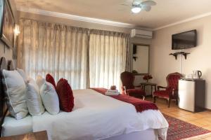 um quarto com uma grande cama branca com almofadas vermelhas em Mistique Waters Guesthouse em Parys