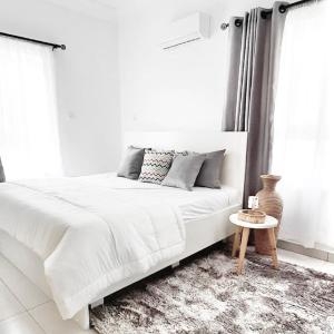 Dormitorio blanco con cama blanca y mesa en Lekki FootPrint, Lekki Phase1 en Lekki