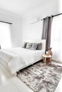 ein weißes Schlafzimmer mit einem großen Bett und einem Teppich in der Unterkunft Lekki FootPrint, Lekki Phase1 in Lekki