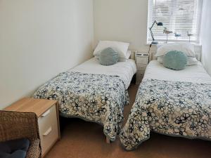 a bedroom with two beds and a table and a window at Seascape - St Catherines Court in Fowey
