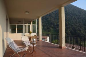 uma varanda com 2 cadeiras, uma mesa e uma montanha em Roby's House Casa Vacanze - Affiliato Best-Incoming em Viadanica Colognola