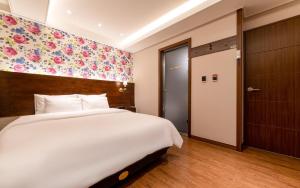 a bedroom with a large white bed and a floral wall at Hotel MoMo in Busan
