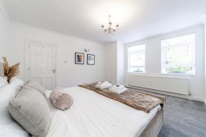 a white bedroom with a large bed and a chandelier at Fantastic 2BR flat wpriv Gdn, Crouch End in London