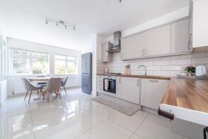 a kitchen with white cabinets and a table with chairs at Fantastic 2BR flat wpriv Gdn, Crouch End in London