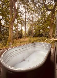 a bath tub sitting on a deck with a tree at Bodos’ Shepards Hut in Durham