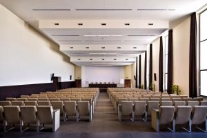 una sala de conferencias vacía con filas de sillas y un podio en TH Assisi - Hotel Cenacolo en Assisi