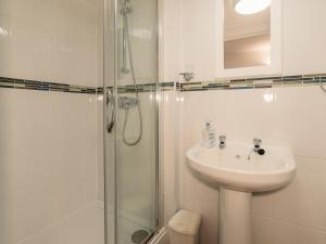 ein weißes Badezimmer mit Waschbecken und Dusche in der Unterkunft The Pool House in Tywardreath