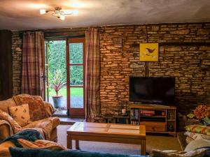 a living room with a tv and a stone wall at Greig House Farm in Llangattock Lingoed