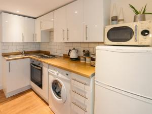 eine Küche mit weißen Schränken und einer Waschmaschine und einem Trockner in der Unterkunft The Pool House in Tywardreath