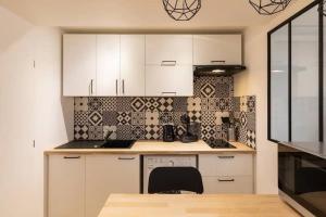 a kitchen with white cabinets and a black and white tiles at Le Flesselles - Hyper centre - Calme et cosy in Lyon