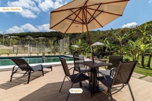 einen Tisch und Stühle mit einem Sonnenschirm neben einem Pool in der Unterkunft Triplex de luxo na Serra de Guaramiranga por Tactu in Guaramiranga