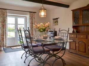 comedor con mesa de cristal y sillas en Hopedene Cottage, en Weare