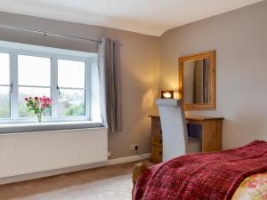 a bedroom with a bed and a desk and a window at Hopedene Cottage in Weare