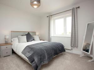 1 dormitorio con cama, ventana y espejo en Fox Lodge en Crantock