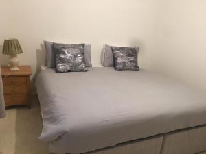 a white bed with two pillows and a night stand at Smarty Angel in Bournemouth