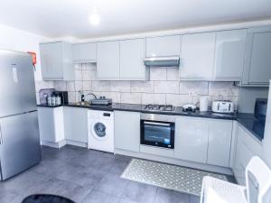 a kitchen with white cabinets and a washer and dryer at 3 bedrooms House with nice park view in Thamesmead