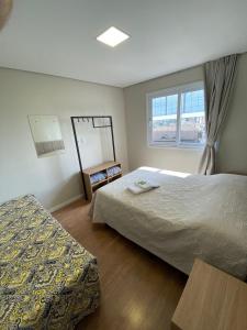um quarto de hotel com duas camas e uma janela em 4 Apartamentos amplos e novos, 86m e 45m, excelente localização, garagem, 350Mb de internet em Bento Gonçalves