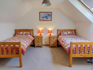2 Einzelbetten in einem Schlafzimmer im Dachgeschoss mit 2 Lampen in der Unterkunft Harbour Hill in Chickerell