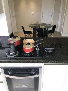 una cocina con fogones con ollas y sartenes. en 4 Apartamentos amplos e novos, 86m e 45m, excelente localização, garagem, 350Mb de internet, en Bento Gonçalves