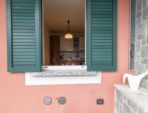 a window with green shutters on a pink house at Villa Roberta in Mandello del Lario +151 photos