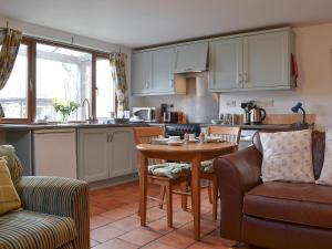 a kitchen with a table and chairs and a kitchen with white cabinets at Gardeners Cottage - Ukc4299 in Littleham