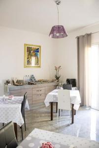 a dining room with white tables and a pendant light at Blu Mare Lampedusa Bed And Breakfast in Lampedusa