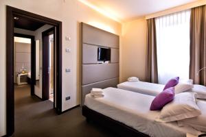 um quarto de hotel com duas camas com almofadas roxas em TH Assisi - Hotel Cenacolo em Assis