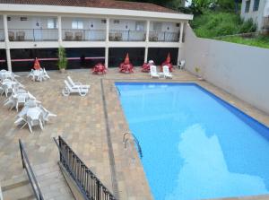 um hotel com piscina e cadeiras e um edifício em Hotel São Luiz em Águas de Lindoia