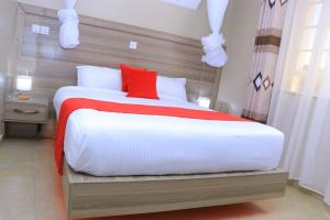 a bedroom with a large white bed with red pillows at Ohm Village Inn(OVI) in Kitui