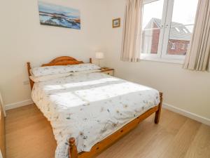 a bedroom with a bed with a white comforter and a window at Tweed Apartment in Darnick