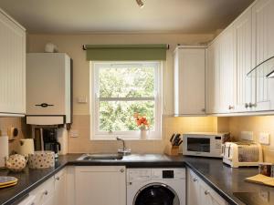 a kitchen with white cabinets and a sink and a window at Flat 4 in Keswick