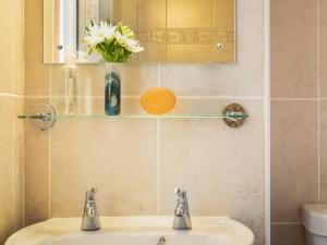 a bathroom with a sink and a vase with white flowers at Flat 4 in Keswick