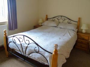 1 dormitorio con 1 cama grande con sábanas y almohadas blancas en Tan Rallt Barn, en Tregarth