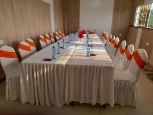 a long table in a room with orange and white chairs at Ohm Village Inn(OVI) in Kitui