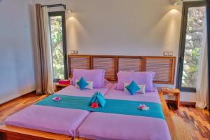 una camera da letto con un grande letto con cuscini viola di ANJARA LODGE Villa de 3 chambres a Nosy Be