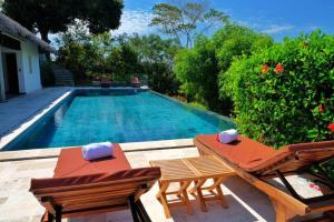 a swimming pool with two chairs and a table at ANJARA LODGE Villa de 3 chambres in Nosy Be