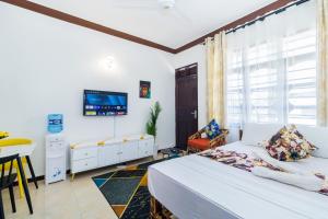 a bedroom with a bed and a tv on the wall at Shikamoo Spacious Studio Nyali in Mombasa