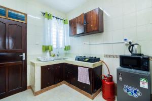 a small kitchen with a stove and a refrigerator at Shikamoo Spacious Studio Nyali in Mombasa +1 photo