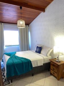 1 dormitorio con cama, lámpara y ventana en Casa em Cabo Frio, en Cabo Frío