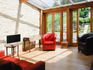 sala de estar con silla roja y piano en The Byre, en West Stour