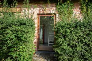 una casa de ladrillo con una puerta de madera y algunos arbustos en Rooms De Voerman, en Ypres