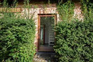 a brick house with a wooden door and some bushes at Rooms De Voerman in Ieper